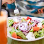 Colorful salad with fresh vegetables and a refreshing drink on a table.