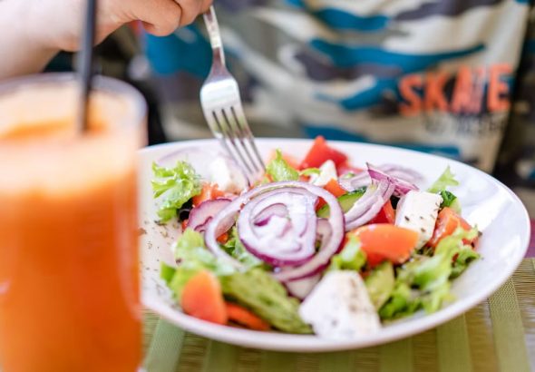 Colorful salad with fresh vegetables and a refreshing drink on a table.